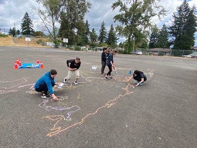 volunteers drawing the outline of the maps in chalk